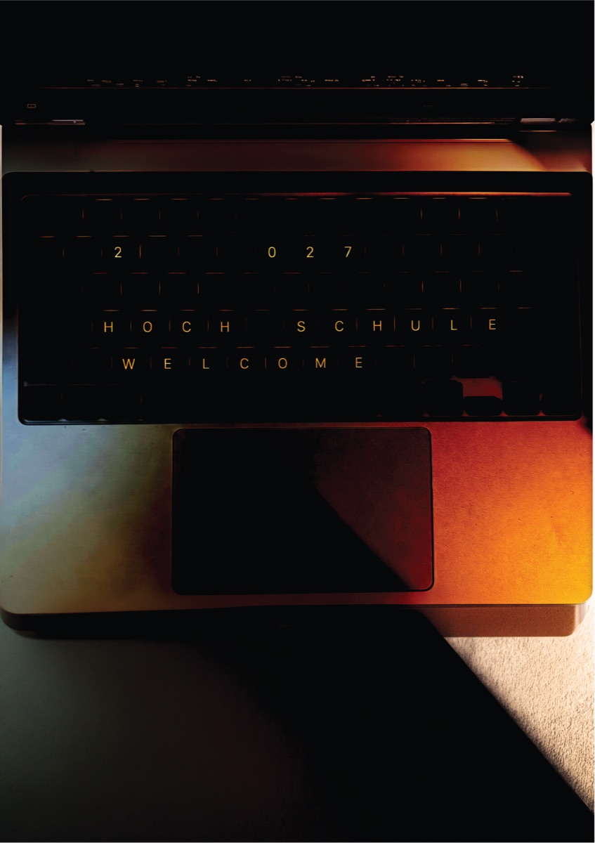 Poster: an overhead photograph of an open laptop lit in warm orange and red, carrying only the letterspaced lines 2027, HOCHSCHULE and WELCOME in thin type.